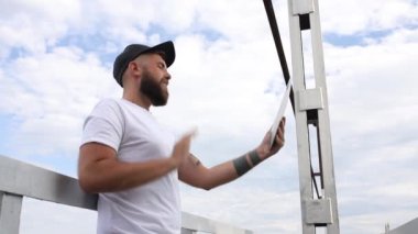 Genç stil sahibi adam açık havada tablet kullanıyor.