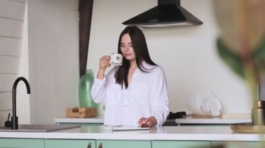 Kız sabah mutfakta sosyal ağları kontrol ediyor.