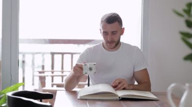 Adam masada otururken bir kitap okuyor.