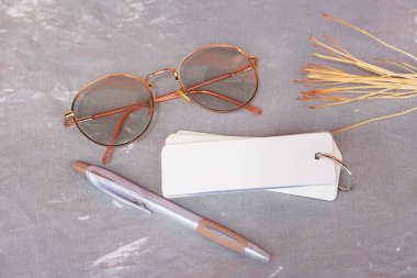 Gri kumaş zemin üzerine boş sayfaları olan boş spiral not defteri. Kalem, gözlük ve kurumuş dallarla süslenmiş. En küçük kırtasiye kurulumu, modelleme, tasarım veya yaratıcı sunum için mükemmel                               