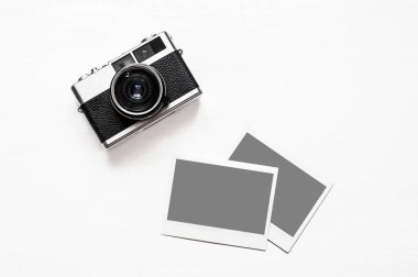 Resimlerinizi Flatlay vintage retro kamera boş anlık kağıt fotoğraf ahşap beyaz zemin üzerine yerleştirilir. Üstten görünüm