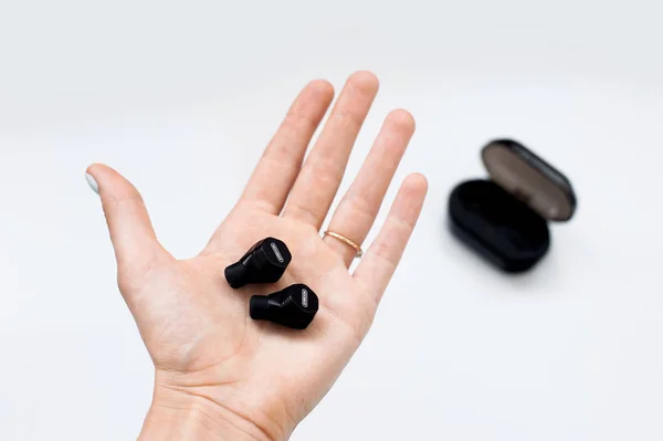 Gerçek radyo earphones elinde dava beyaz arka plan üzerinde şarj ile siyah. Fitness Spor kablosuz kulaklık. Yeni kulaklıkları