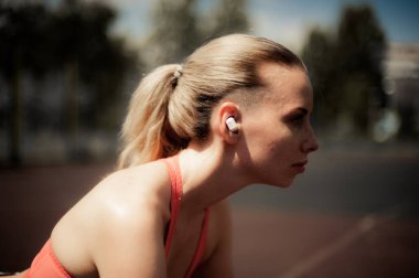 Kablosuz kulaklık müzik dinleme, sokakta Egzersiz egzersizleri yapıyor fitness kadın. Spor stil Bluetooth kulaklık