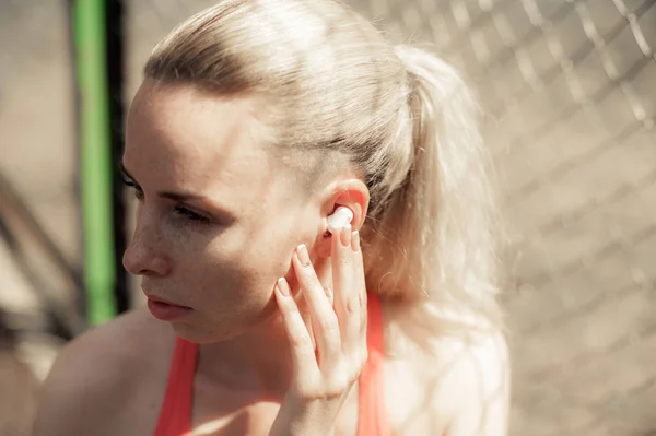 Kablosuz kulaklık müzik dinleme, sokakta Egzersiz egzersizleri yapıyor fitness kadın. Spor stil Bluetooth kulaklık