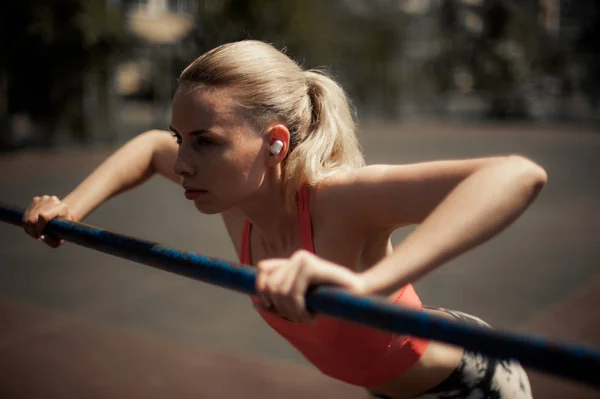 Kablosuz kulaklık müzik dinleme, sokakta Egzersiz egzersizleri yapıyor fitness kadın. Spor stil Bluetooth kulaklık