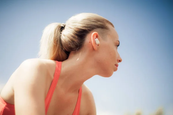 Fitness Woman Listening Music in Wireless Headphones, Doing Workout Exercises On Street. Sport style Bluetooth earphones