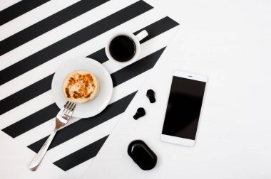Smartphone sahte kadar fincan kahve, fırın, çizgili siyah ve beyaz arka plan üzerinde izole radyo earphones ile şık minimalist çalışma alanı. Düz yatıyordu stil üstten görünüm. 