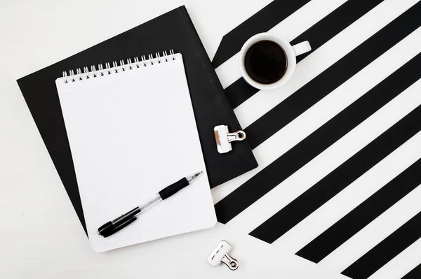 Kitap, defter, kalem, kahve, çizgili siyah ve beyaz arka plan üzerinde izole ile şık minimalist çalışma alanı. Düz yatıyordu stil üstten görünüm. Kare kırpma. 