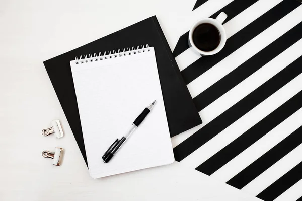 Kitap, defter, kalem, kahve, çizgili siyah ve beyaz arka plan üzerinde izole ile şık minimalist çalışma alanı. Düz yatıyordu stil üstten görünüm. Kare kırpma. 