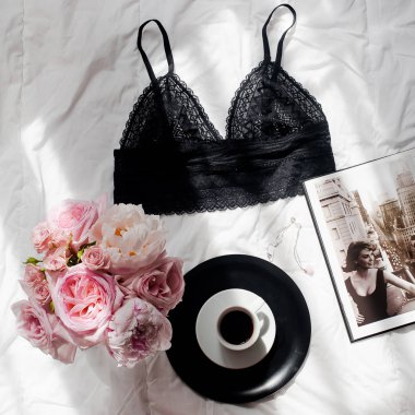 Düz lay, dergiler, sosyal medya. Üstten görünüm siyah dantel iç çamaşırı. Güzellik blog kavramı. Kadın moda aksesuarları, iç çamaşırı, buket gül ve pions, beyaz yatak zemin üzerine kahve
