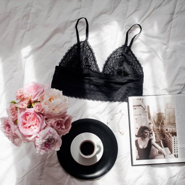 Düz lay, dergiler, sosyal medya. Üstten görünüm siyah dantel iç çamaşırı. Güzellik blog kavramı. Kadın moda aksesuarları, iç çamaşırı, buket gül ve pions, beyaz yatak zemin üzerine kahve