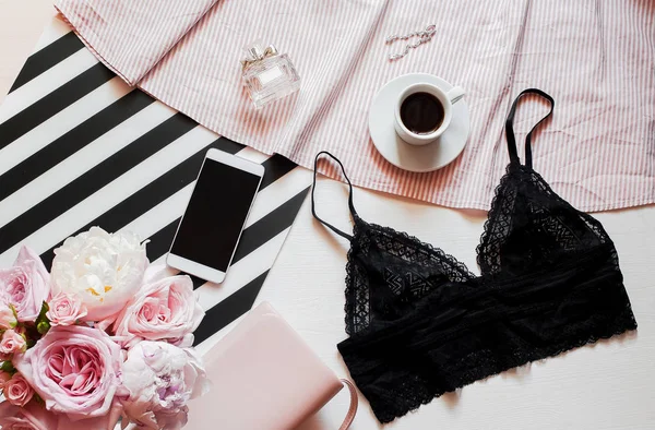 Flat lag, tijdschriften, sociale media. Bovenaanzicht black lace lingerie. Beauty blog concept. Vrouw mode-accessoires, ondergoed, boeket van rozen en pionen, schaduwplaatsen, sieraden, koffie op witte bed achtergrond — Stockfoto