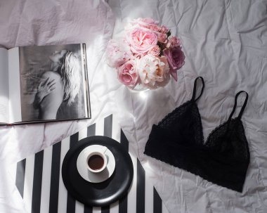 Düz lay, dergiler, sosyal medya. Üstten görünüm siyah dantel iç çamaşırı. Güzellik blog kavramı. Kadın moda aksesuarları, iç çamaşırı, buket gül ve pions, beyaz yatak zemin üzerine kahve.