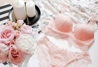 Düz lay, dergiler, sosyal medya. Üstten görünüm pembe dantel iç çamaşırı. Güzellik blog kavramı. Kadın moda aksesuarları, iç çamaşırı, buket gül ve pions, parfüm, takı, beyaz yatak zemin üzerine kahve