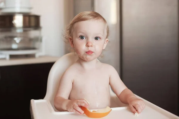A kislány enni dinnye. Vicces nevető gyermek a konyhában. Vidám gyerek a etetőszék — Stock Fotó