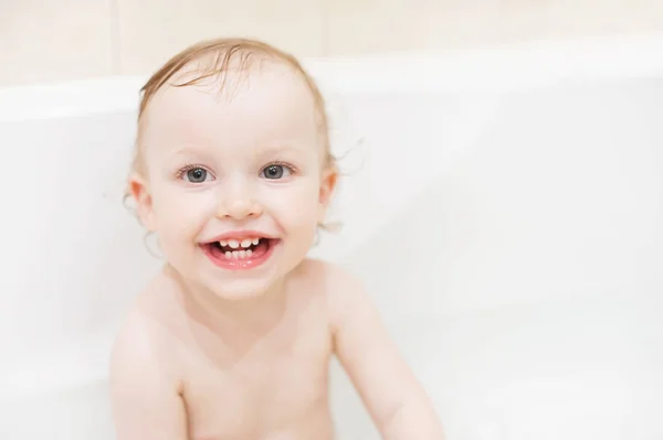 Boldog aranyos kislány a fürdőszobában. Mosolygó gyerek játszik a habot. Gyermek nevetve mosás haj sampon. — Stock Fotó