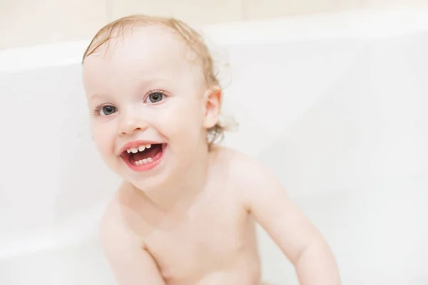 Feliz niña linda en el baño. Chico sonriente jugando con espuma. Niño riéndose lavando el cabello con champú . —  Fotos de Stock