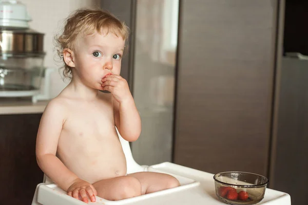 Eszik szamóca kislány. Vicces nevető gyermek a konyhában. Vidám gyerek a etetőszék — Stock Fotó