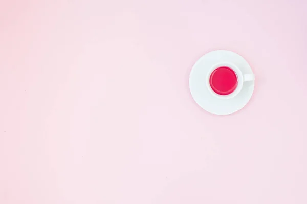 Tasse Tee auf pastellrosa Hintergrund. Weiblicher Arbeitsplatz. flache Verlegung, minimales Konzept, Draufsicht. — Stockfoto
