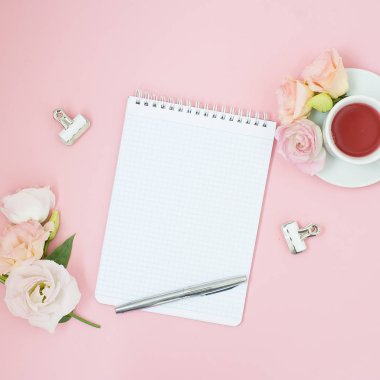 Kadınsı office çalışma alanı. Defter ile boşaltmak. Düz yatıyordu, sosyal medya, üstten görünüm. Pembe çiçekler, pastel pembe bir arka plan üzerinde çay.