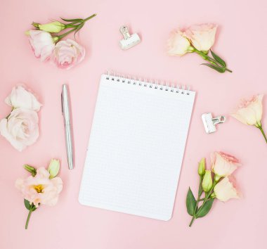 Kadınsı office çalışma alanı. Defter ile boşaltmak. Düz yatıyordu, sosyal medya, üstten görünüm. Pembe çiçekler, pastel pembe bir arka plan üzerinde çay.