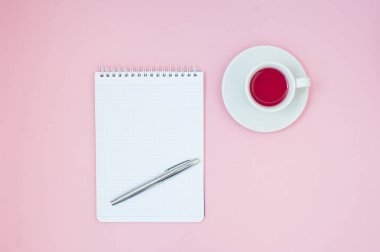 Fincan çay ve defter ile boşaltmak pastel pembe bir arka plan üzerinde. Kadınsı çalışma alanı. Düz yatıyordu, minimal kavramı, üstten görünüm. Yapılacaklar listesi düğün. Mockup planlayıcısı.