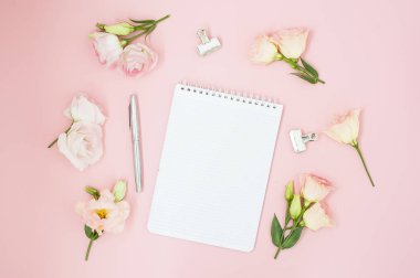 Kadınsı office çalışma alanı. Defter ile boşaltmak. Düz yatıyordu, sosyal medya, üstten görünüm. Pembe çiçekler, pastel pembe bir arka plan üzerinde çay.
