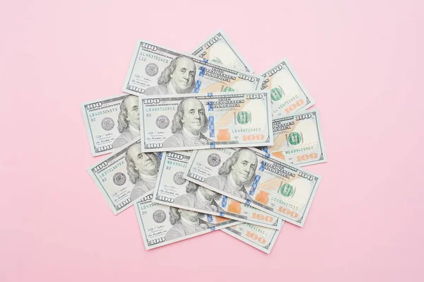 Nueva pila de billetes de cien dólares. Primer plano del billete sobre fondo rosa pastel. Concepto de dinero — Foto de Stock