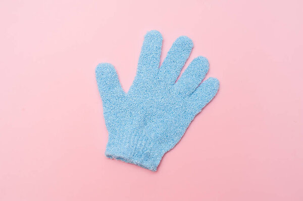 Woman exfoliating hydro glove on pink background. Massage and scrub. Health, spa and beauty concept.