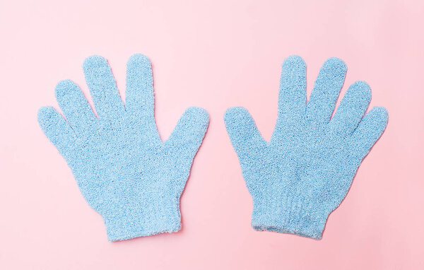 Woman exfoliating hydro glove on pink background. Massage and scrub. Health, spa and beauty concept.