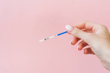 Hamilelik testi pembe bir arka plan üzerinde kadın elinde. Olumlu sonuç. 