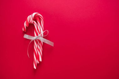 Noel ve yeni yıl tebrik kartı için kırmızı zemin üzerine gümüş yay ile baston şekerler.