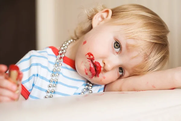 小搞笑金发碧眼的女婴用妈妈的红色口红化妆嘴唇。学会做女人。快乐童年的概念. — 图库照片