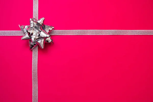 Серебряные ленты с луком на красном фоне. Рождественский подарок. Продажи . — стоковое фото