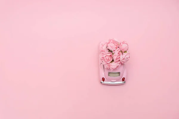 Rosa Retro-Spielzeugauto liefert Blumenstrauß Box auf rosa Hintergrund. 14. Februar Karte für den Valentinstag. Blumenlieferung. 8. März, internationaler fröhlicher Frauentag. — Stockfoto