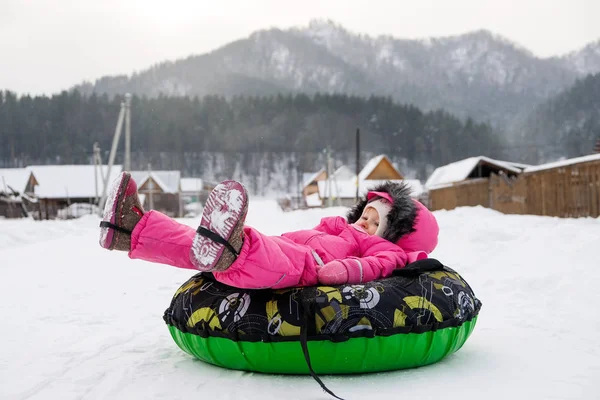 Little girl in  snow tube. Winter tubing. Winter leisure activity concept. Family winter fun