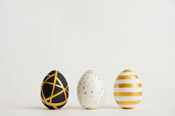 Three Easter golden decorated eggs isolated on white background. Minimal easter concept. Happy Easter card with copy space — Stock Photo, Image