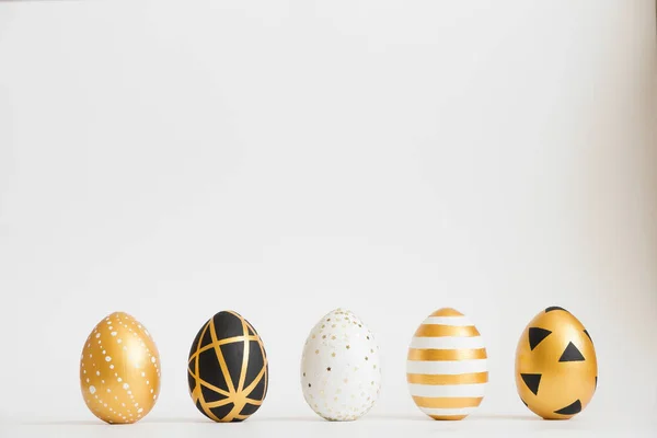 Os ovos decorados de ouro de Páscoa estão em uma linha no fundo branco. Conceito mínimo de Páscoa . — Fotografia de Stock