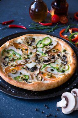 Mantar, biber ve domates koyu mavi taş masa ve çeşitli maddeler ile geleneksel İtalyan pizza pizza ile düz yatıyordu: mantar, domates, yağ, karabiber, tuz, fesleğen, zeytinyağı