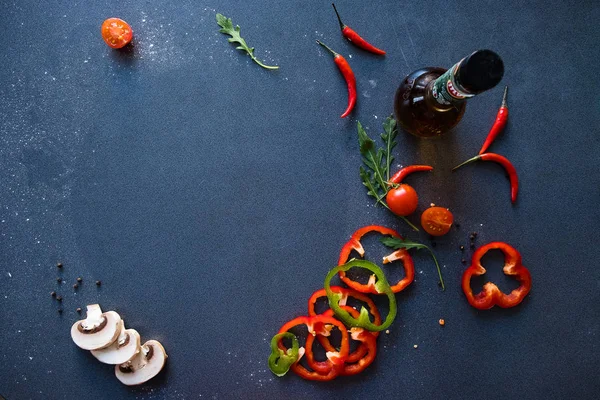 Flat lay with traditional Italian pizza pizza with mushrooms, pepper and tomatoes on dark blue stone table and various ingredients: mushrooms, tomatoes, oil, pepper, salt, basil, olive — Stock Photo, Image