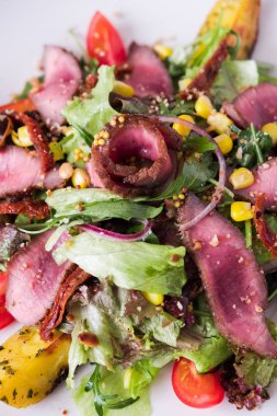 Sıcak et beyaz plateon karanlık taş zemin üzerine Roka Salatası. İngridients aşçı için düz yatırın.