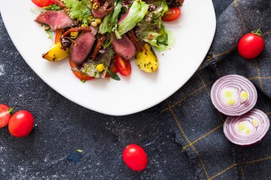 Sıcak et beyaz plateon karanlık taş zemin üzerine Roka Salatası. İngridients aşçı için düz yatırın.