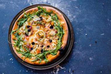 Midye, roka ve parmesan, fesleğen, zeytinyağı koyu mavi taş masada geleneksel İtalyan pizza düz yatırın