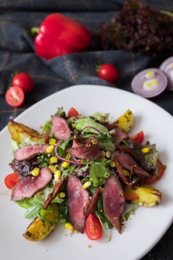 Sıcak et beyaz plateon karanlık taş zemin üzerine Roka Salatası. İngridients aşçı için düz yatırın.