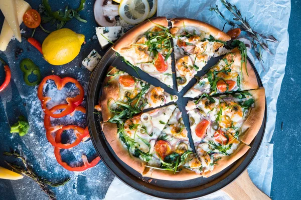 Düz midye, roka ve parmesan ile geleneksel İtalyan pizza koyu mavi taş masa üzerine yatırın. Dilim pizza
