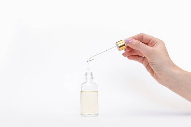 Damlatan cam şişe maketi. Beyaz arka plandaki kozmetik pipetinden yağlı damlalar düşüyor