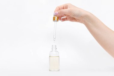Damlatan cam şişe maketi. Beyaz arka plandaki kozmetik pipetinden yağlı damlalar düşüyor