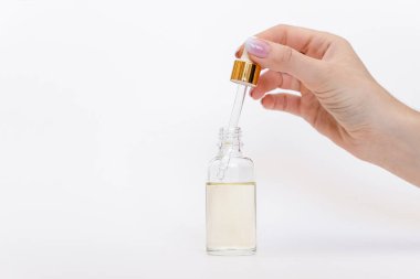 Damlatan cam şişe maketi. Beyaz arka plandaki kozmetik pipetinden yağlı damlalar düşüyor