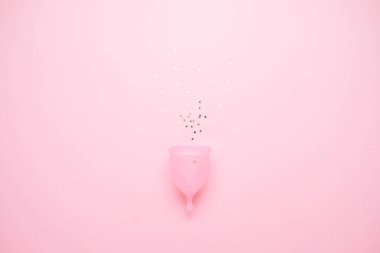 Pembe arka planda adet fincan. Bu dönemde alternatif kadınsı hijyen ürünü. Kadın sağlığı kavramı