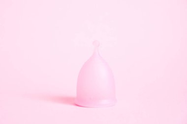 Pembe arka planda adet fincan. Bu dönemde alternatif kadınsı hijyen ürünü. Kadın sağlığı kavramı